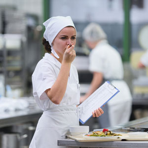 Diätassistentin probiert beim Einsatz in der Küche das frisch zubereitete Essen und kontrolliert die Qualität