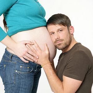 Mann lauscht am Babybauch einer Frau
