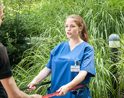 Logopädin macht mit Patienten Stimmübungen mit Terra-Band