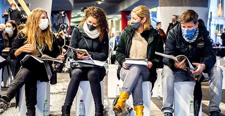 Besucher der Vernissage blättern durch die eigens produzierte Zeitung