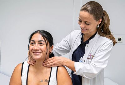 Tastuntersuchung der Schilddrüse: Von hinten kann die Ärztin das Organ der Patientin unterhalb des Kehlkopfs besonders gut abtasten Tastuntersuchung der Schilddrüse: Von hinten kann die Ärztin das Organ der Patientin unterhalb des Kehlkopfs besonders gut abtasten