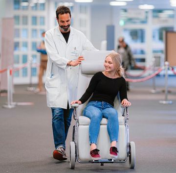Ein Begleiter bringt eine Patientin zu einer Untersuchung